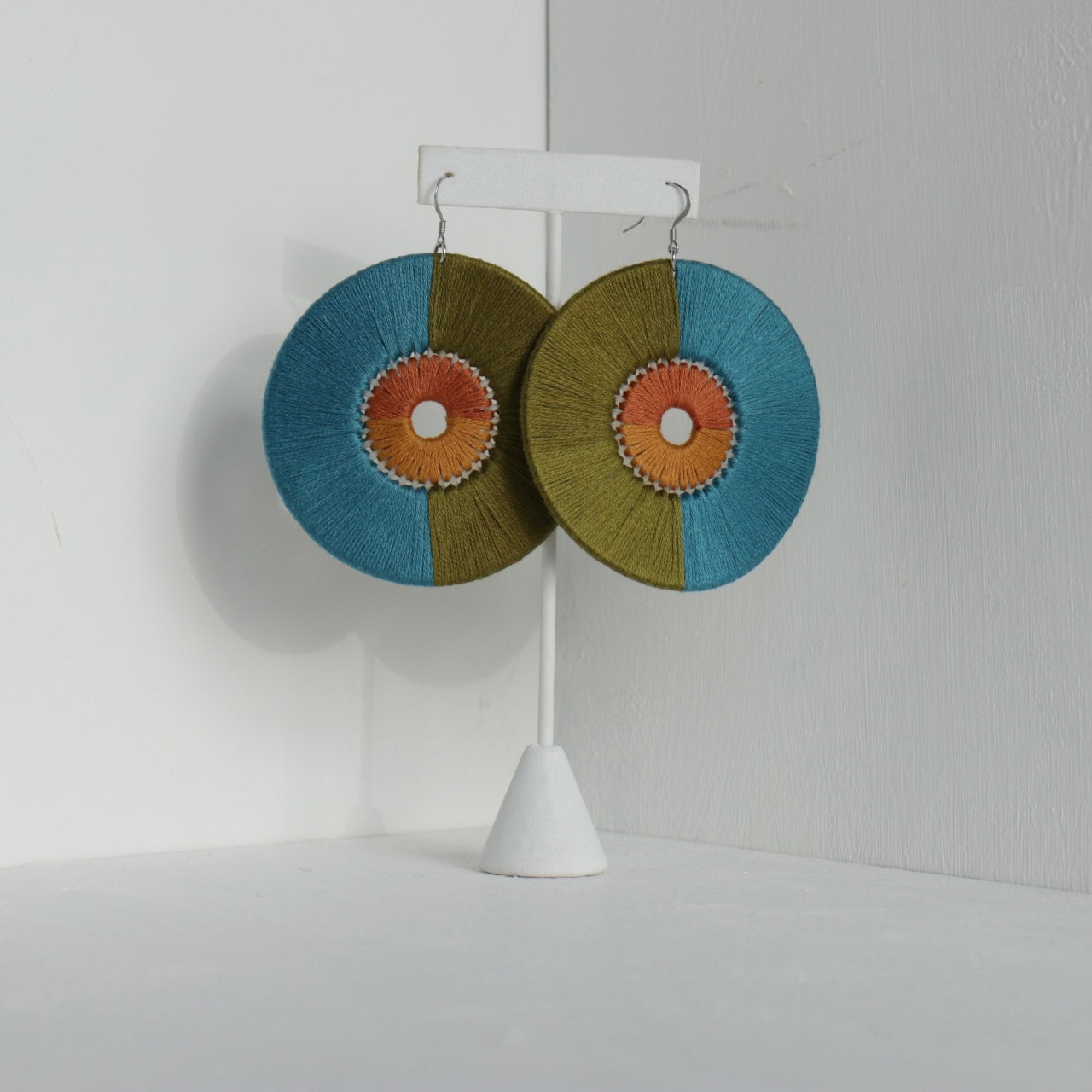 Close-up of the Damek Statement Earrings, featuring a bold geometric design with a balance of earthy green, deep blue, and warm orange hues. Handmade and lightweight.