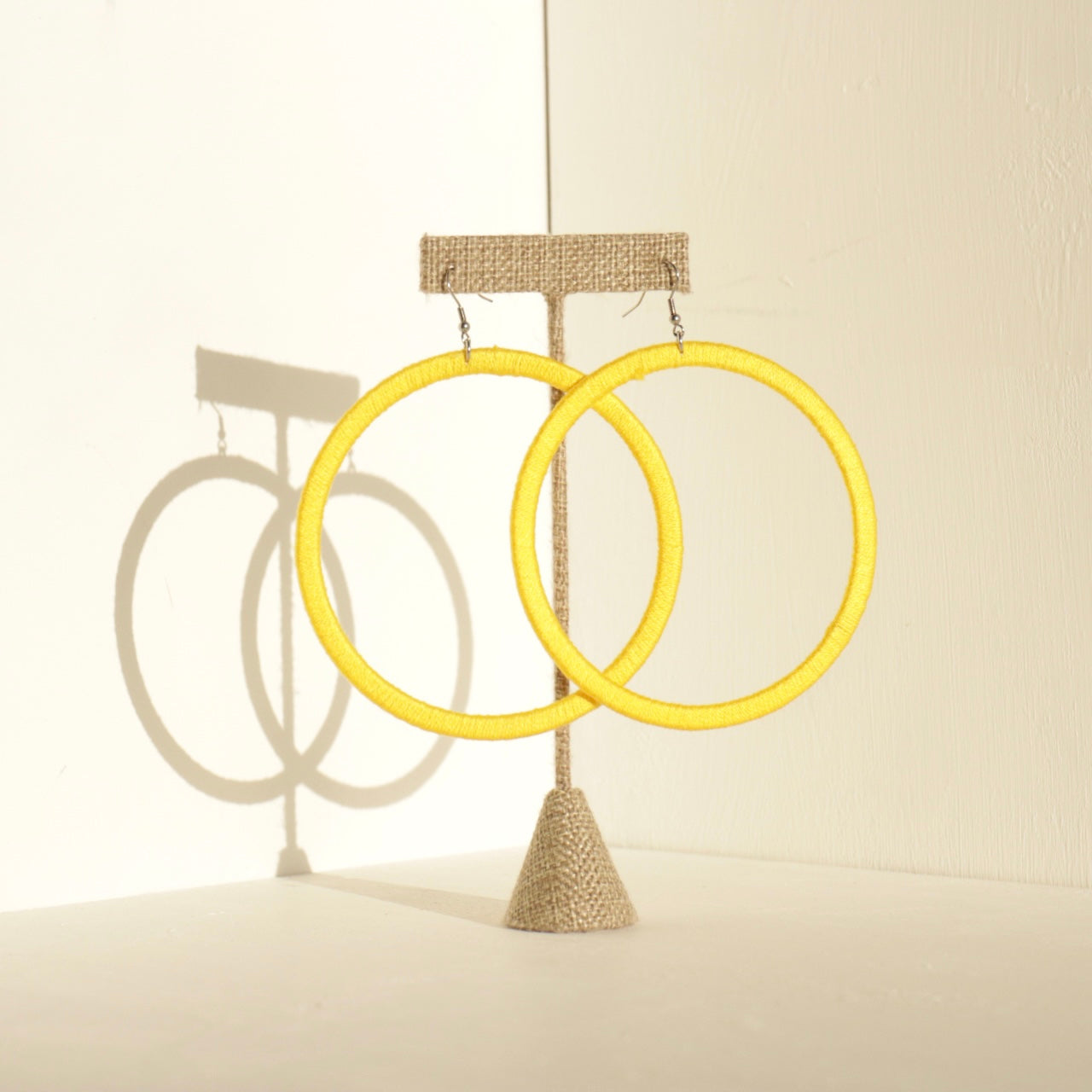 A pair of The Kommon statement hoop earrings from OlaNti Jewelry House, featuring a structured, oversized hoop design, displayed elegantly against a neutral background.
