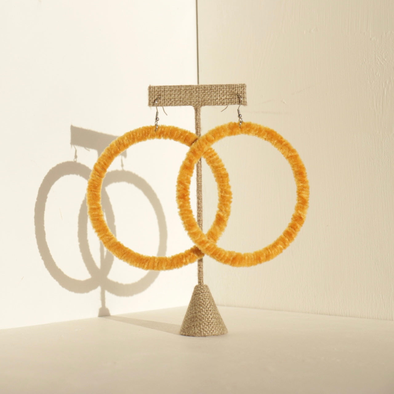 A pair of The Kommon statement hoop earrings from OlaNti Jewelry House, featuring a structured, oversized hoop design, displayed elegantly against a neutral background.