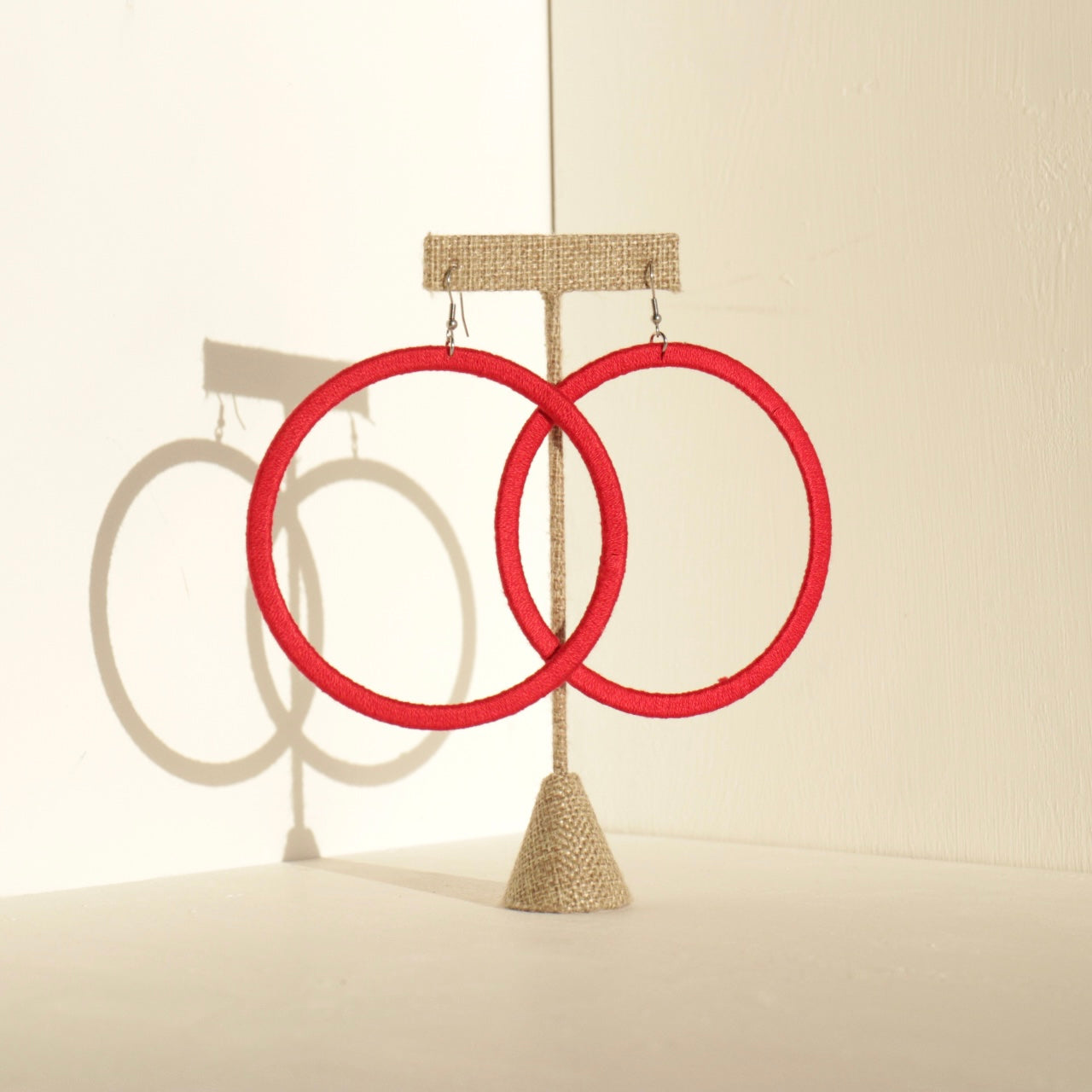 A pair of The Kommon statement hoop earrings from OlaNti Jewelry House, featuring a structured, oversized hoop design, displayed elegantly against a neutral background.