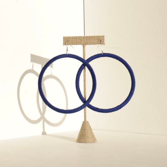 A pair of The Kommon statement hoop earrings from OlaNti Jewelry House, featuring a structured, oversized hoop design, displayed elegantly against a neutral background.