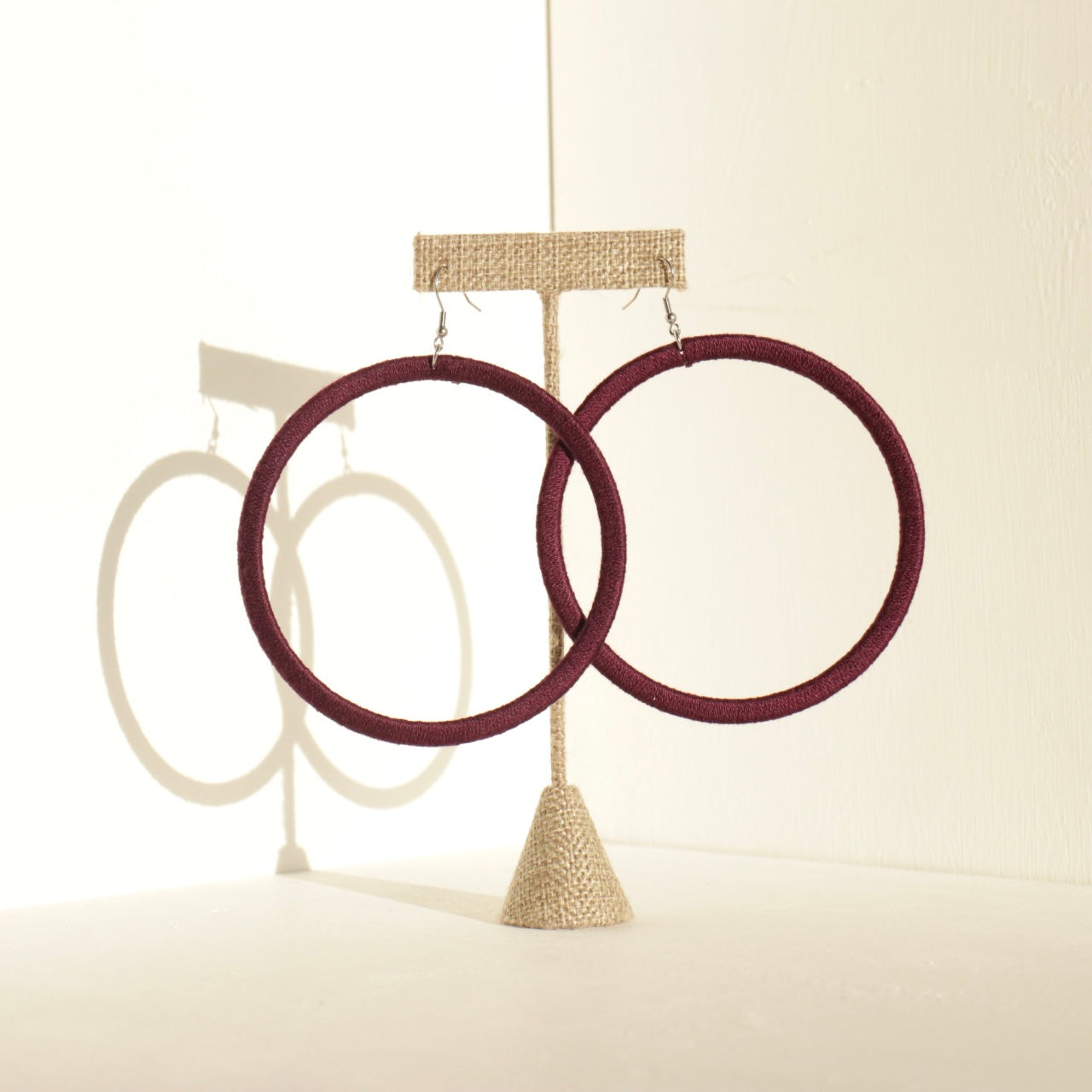 A pair of The Kommon statement hoop earrings from OlaNti Jewelry House, featuring a structured, oversized hoop design, displayed elegantly against a neutral background.