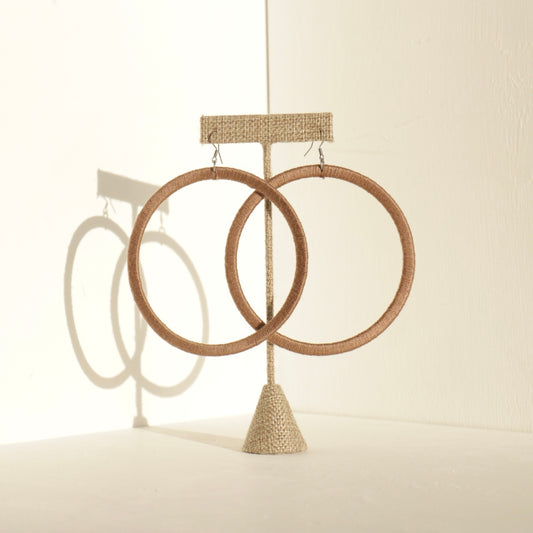 A pair of The Kommon statement hoop earrings from OlaNti Jewelry House, featuring a structured, oversized hoop design, displayed elegantly against a neutral background.