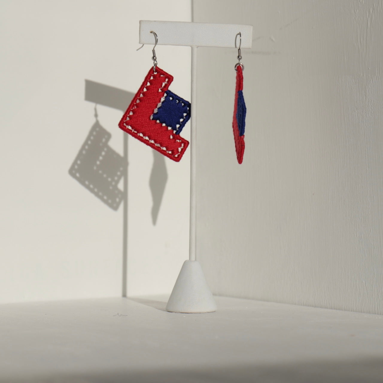 The Baroq earrings displayed on a jewelry stand, featuring bold geometric details