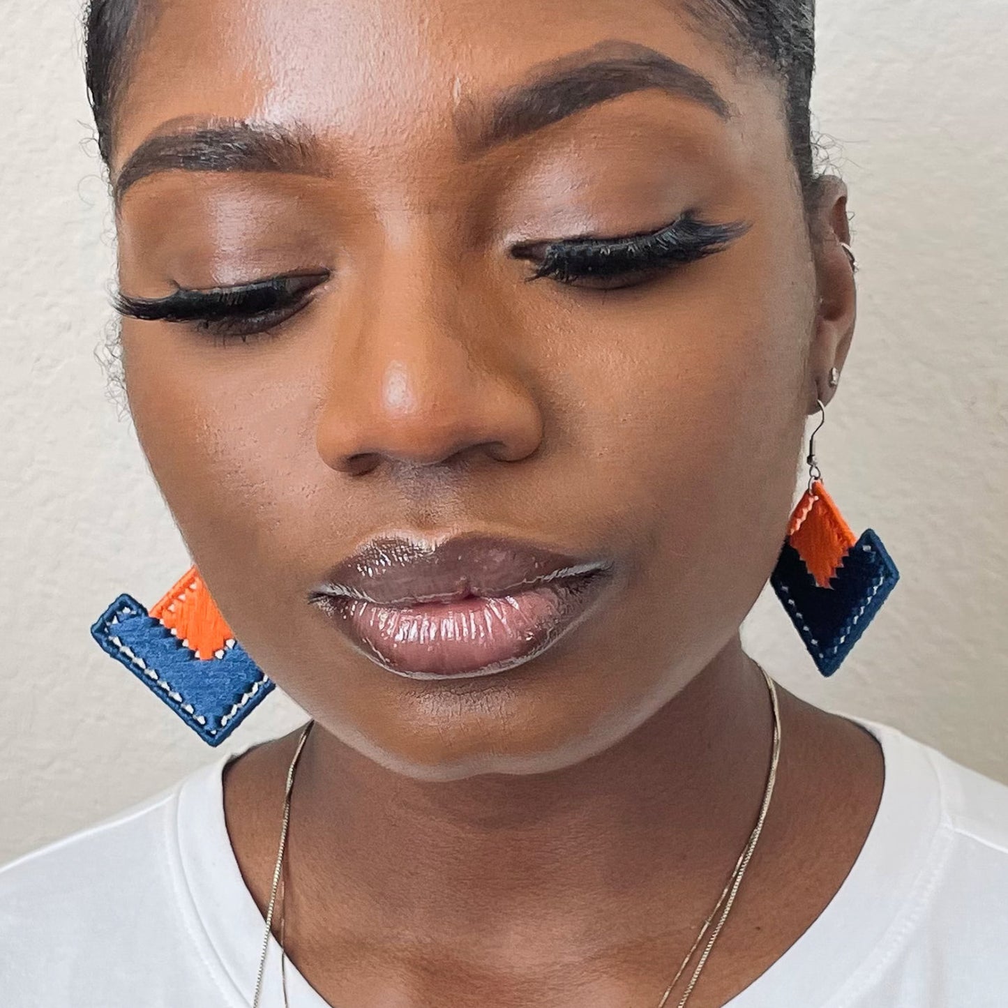 Model wearing The Baroq earrings in orange and blue, adding a structured statement to her look