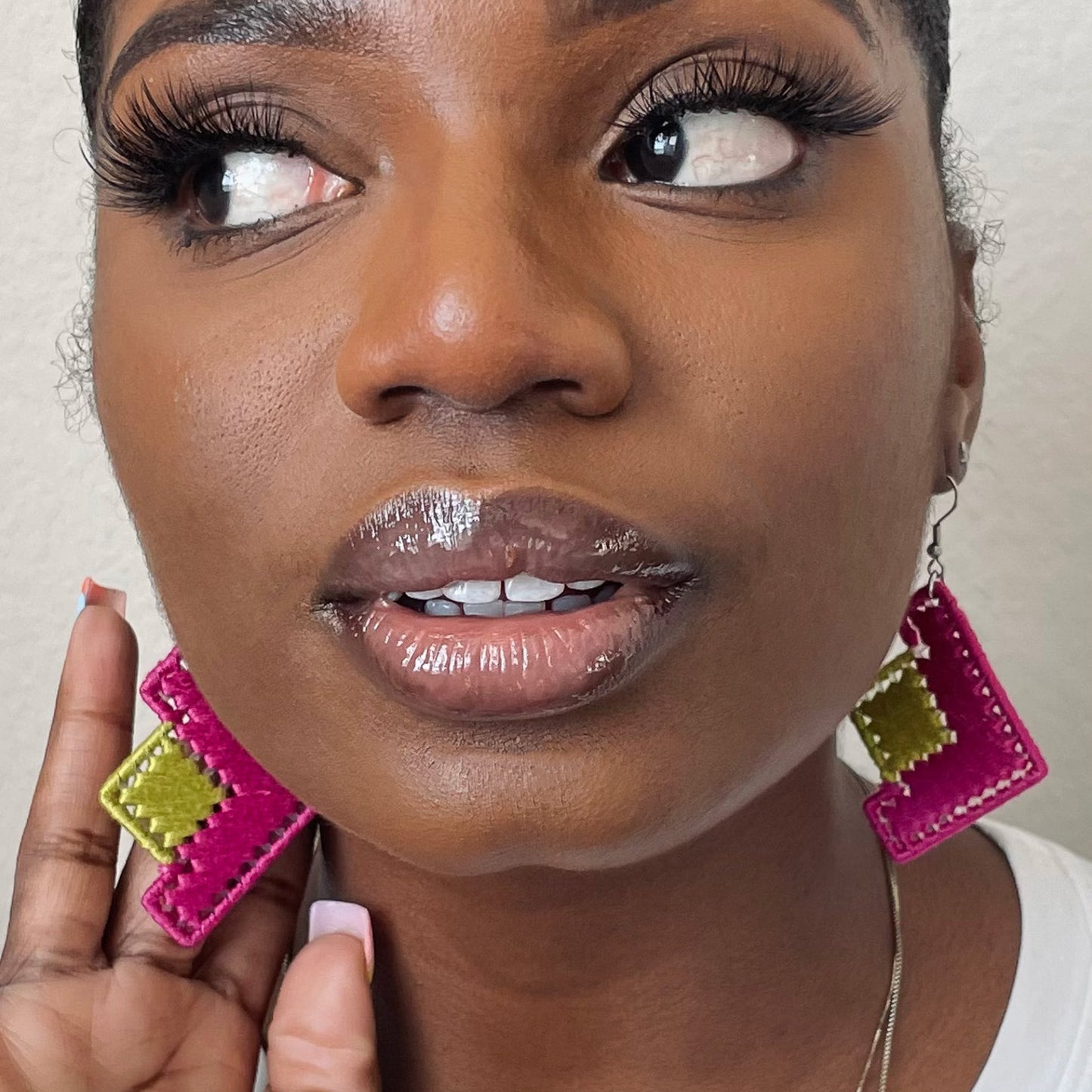 Model wearing The Baroq earrings in pink and green, showcasing their angular design