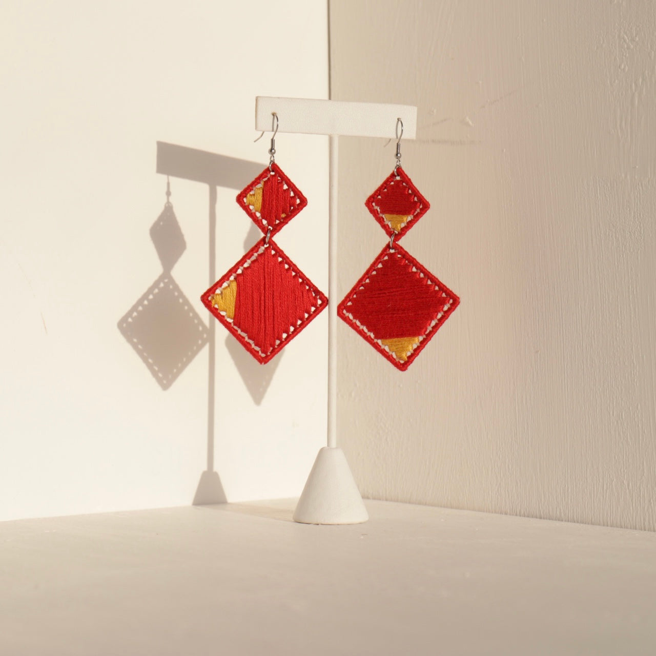 The Brisco earrings in a bold red color, handcrafted geometric design, displayed against a neutral background