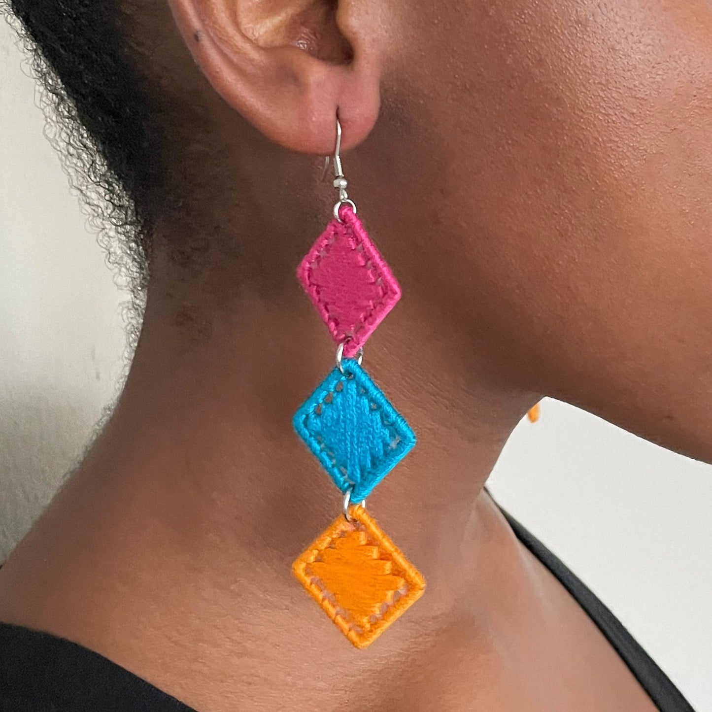 Model wearing The Bunmi earrings, showcasing their cascading design in pink, blue, and orange