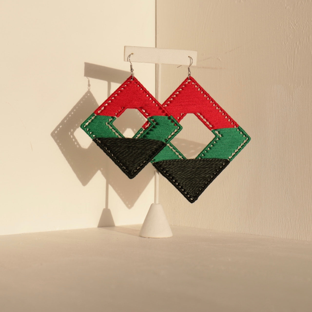 The Joel earrings in red, green, and black displayed against a neutral backdrop