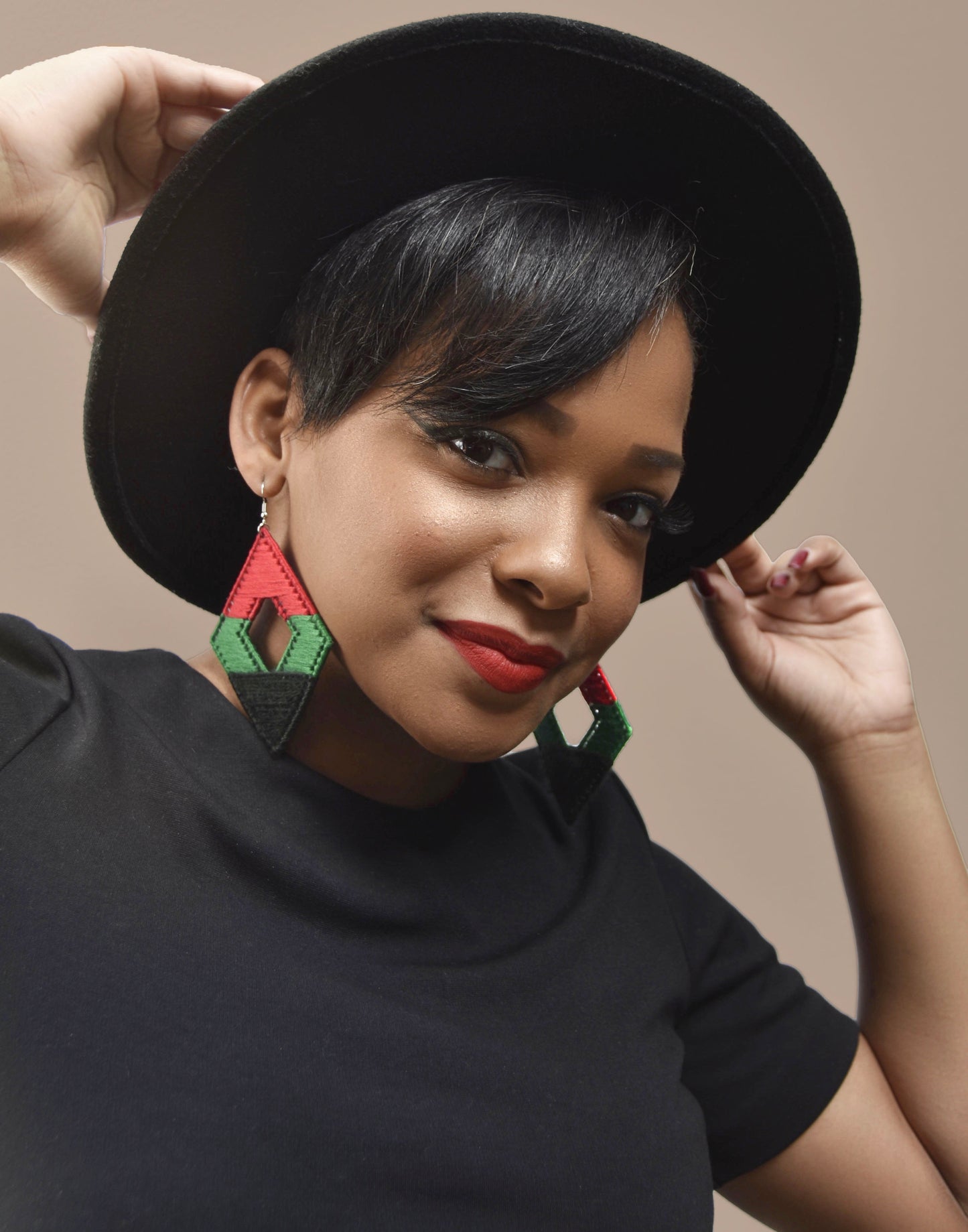 Woman wearing The Joel earrings with a black outfit and a wide-brim hat