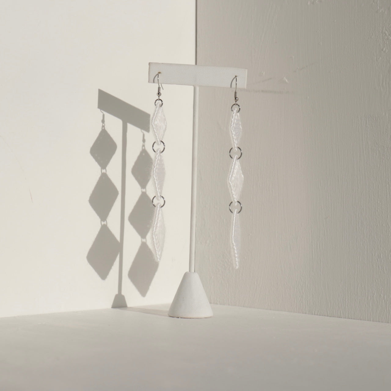 The Kambi earrings in white by OlaNti Houston, crafted with precision for a fluid, cascading effect