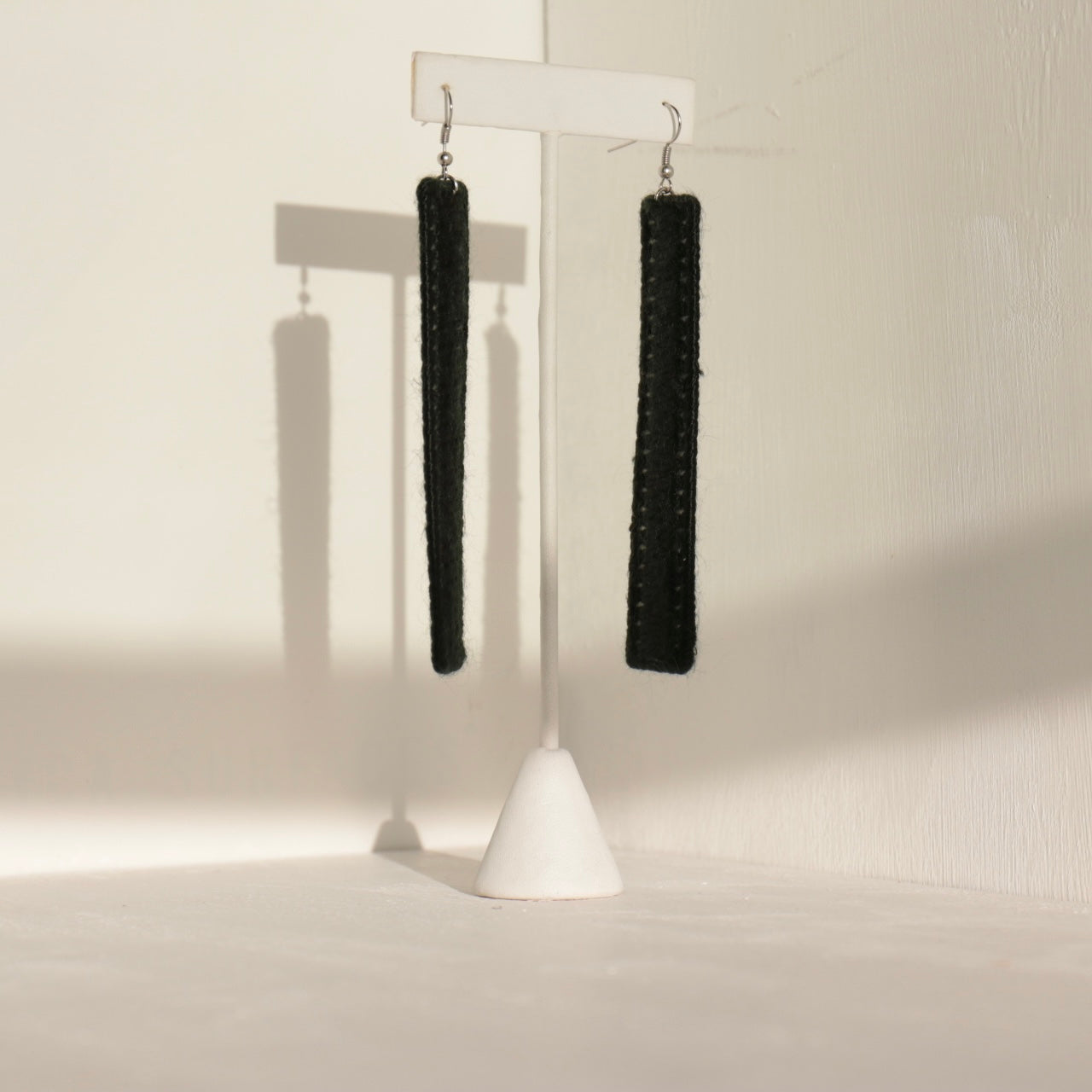 The Kevo earrings in black, showcasing intricate handcrafted details on a neutral backdrop