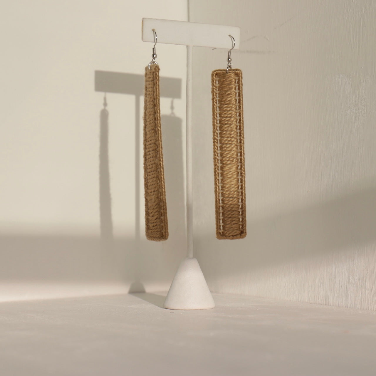 The Kevo earrings in gold displayed on a stand, handcrafted statement jewelry from OlaNti Houston.