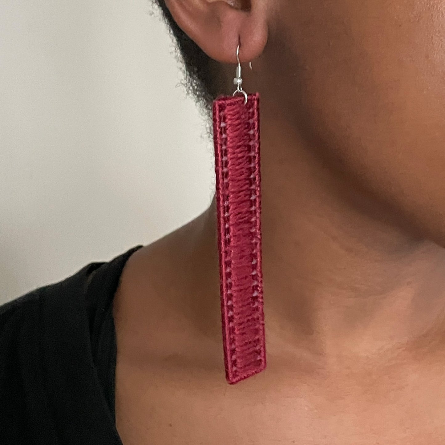 A model wearing The Kevo earrings in red, adding a refined edge to her look