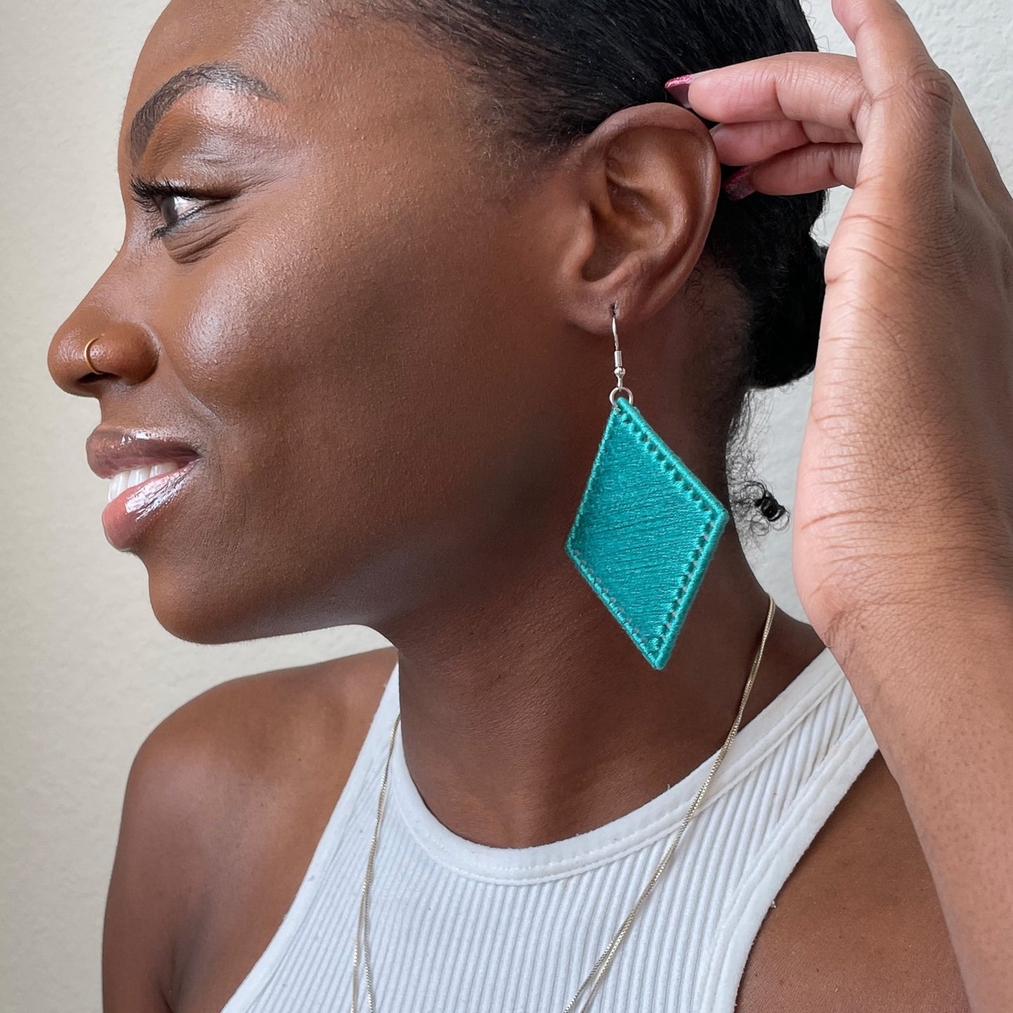 Model wearing green Kwame statement earrings, showcasing their sleek geometric design