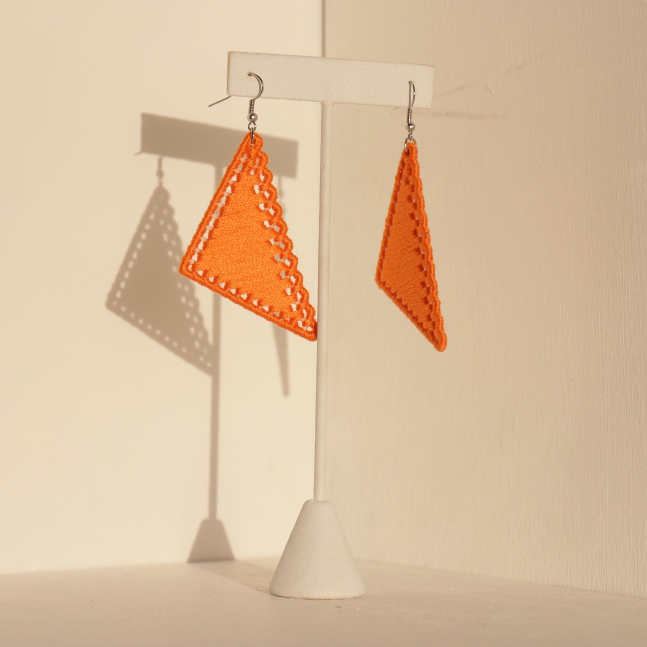 The Kofi earrings in orange by OlaNti Houston, a warm-toned, angular design