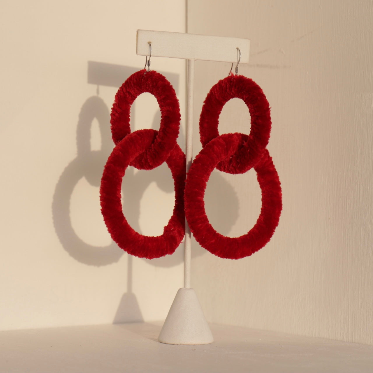 The Valente earrings in vibrant red displayed on a jewelry stan