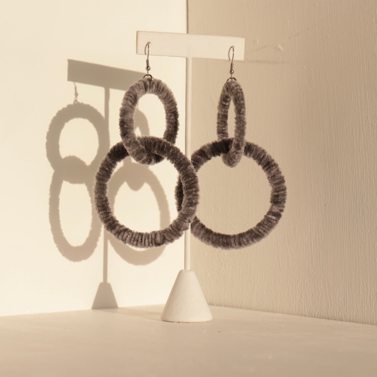 The Valente statement earrings in black displayed on a jewelry stand with soft lighting