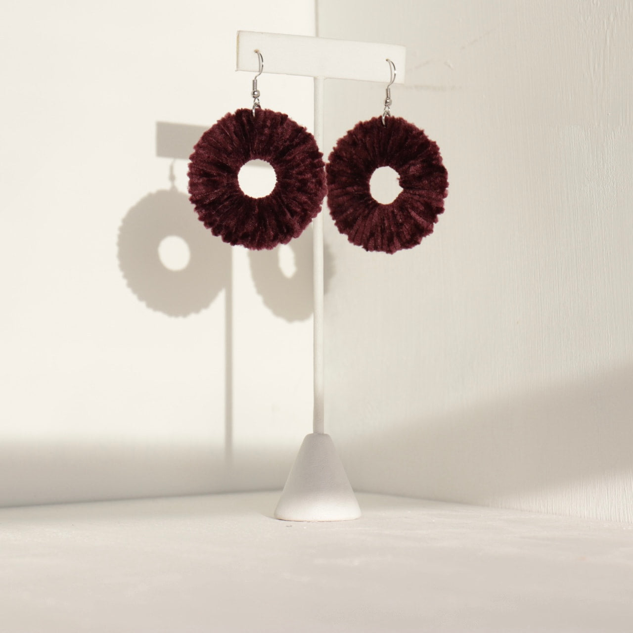 Burgundy Vinny earrings, highlighting their soft texture and handcrafted details.