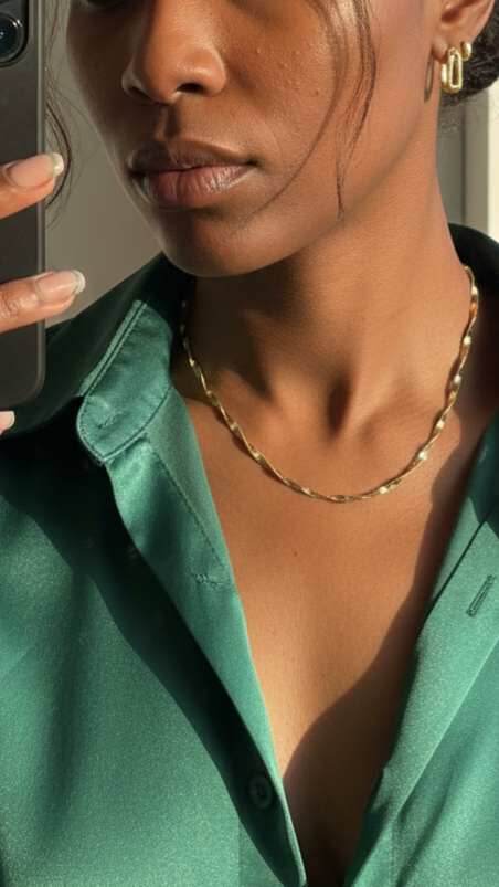 Woman wearing a green shirt and gold necklace, holding a phone.