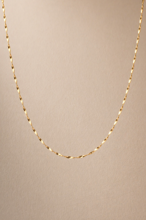 Gold chain necklace on a beige background