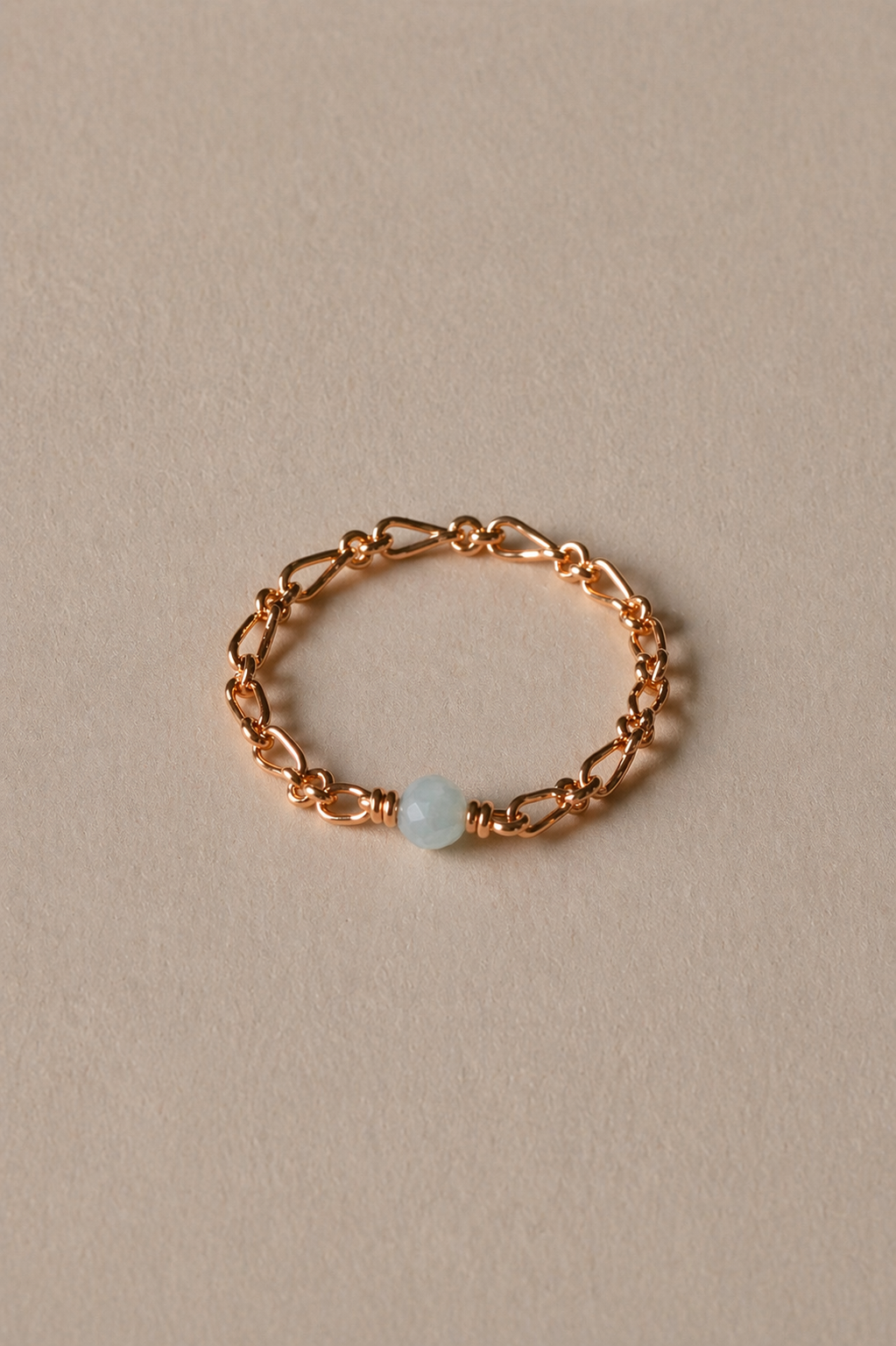 Gold chain ring with a aquamarine stone on a beige background