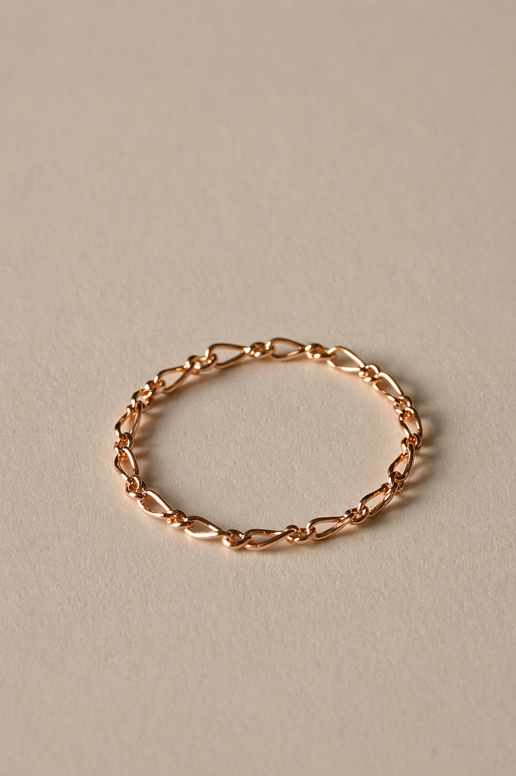 Rose gold chain ring on a beige background