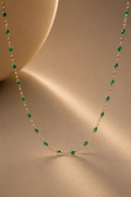 Gold chain with green detail on beige background