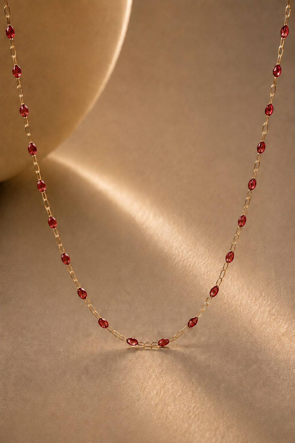 Gold chain with red detail on beige background