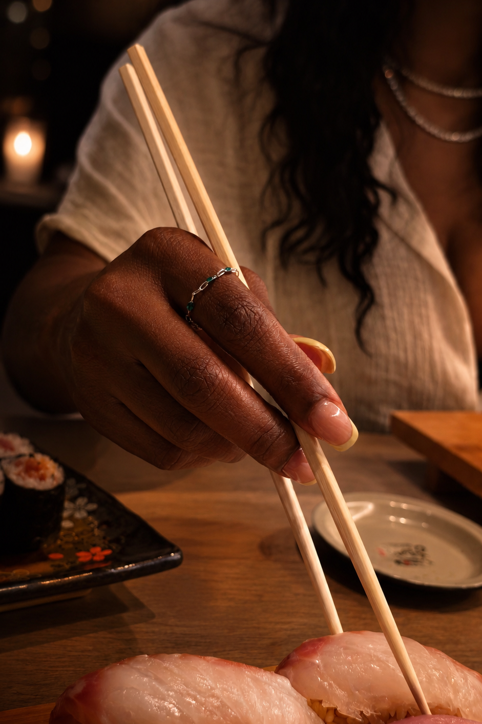 Person using chopsticks to pick up sushi at a restaurant.