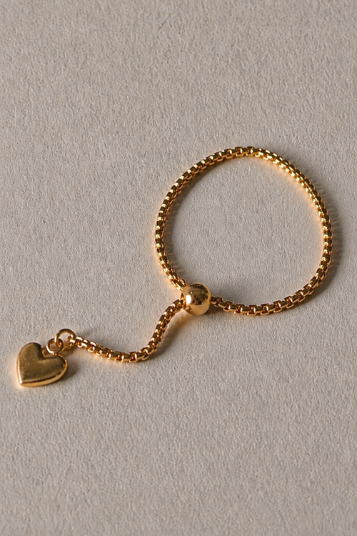Gold adjustable ring with a heart charm on a light gray background