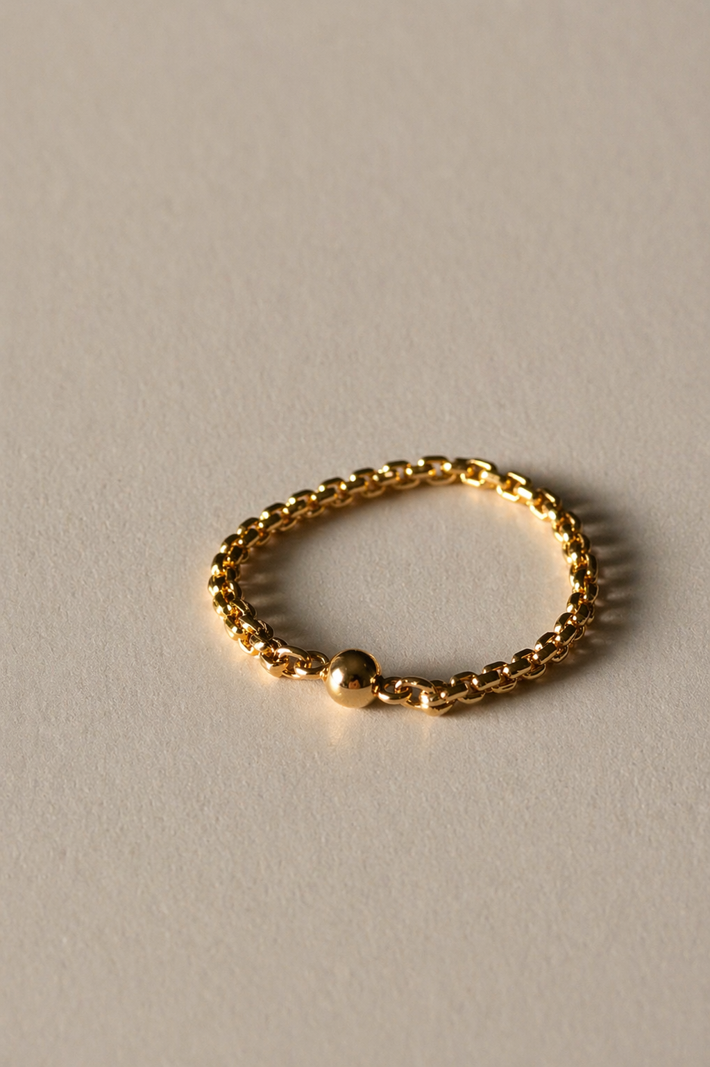 Gold chain ring on a beige background