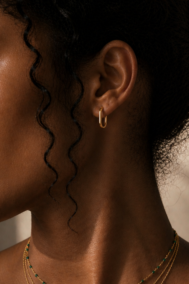 Close-up of a person wearing gold hoop earrings with a blurred background