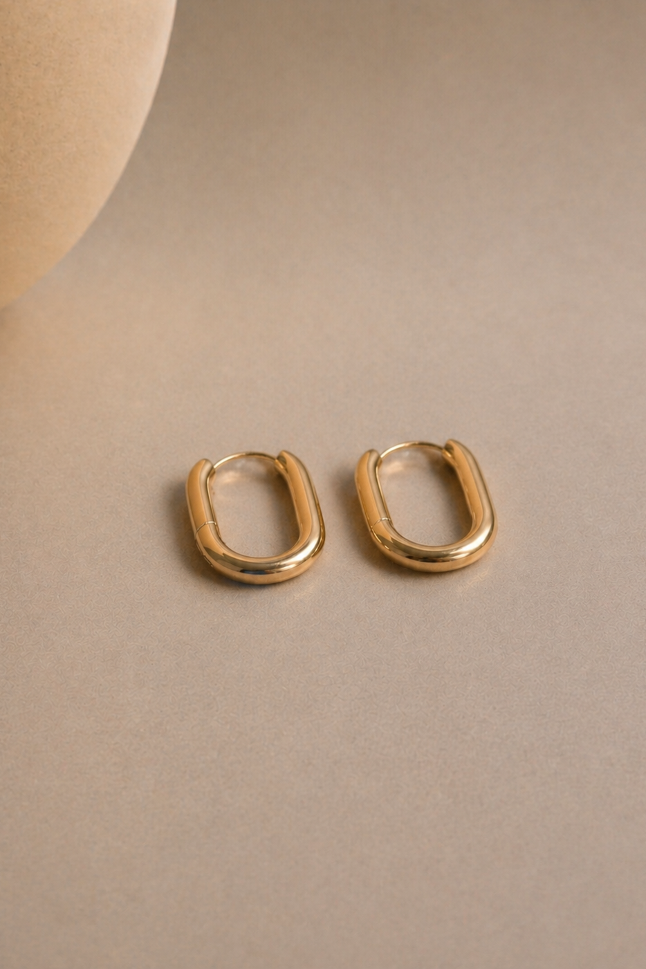 Gold hoop earrings on a beige background