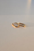 A pair of gold hoop earrings on a plain light gray surface.
