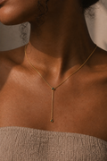 Close-up of a person wearing a delicate gold necklace with a small pendant.