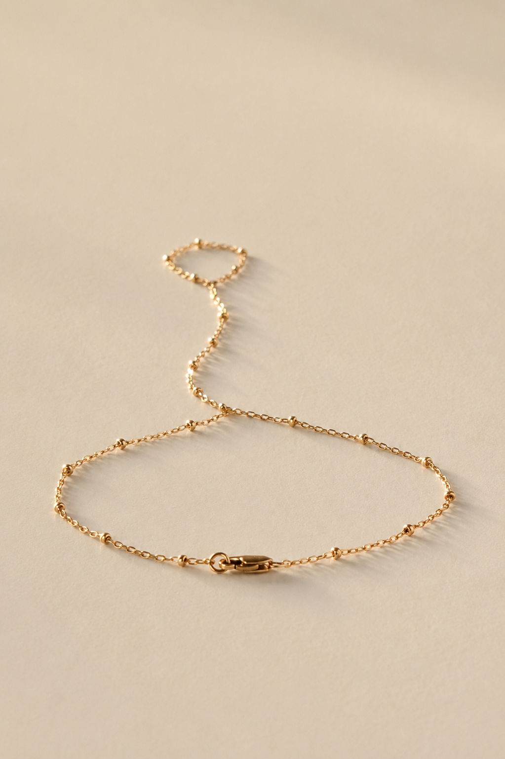 Gold Hand Chan bracelet on a beige background