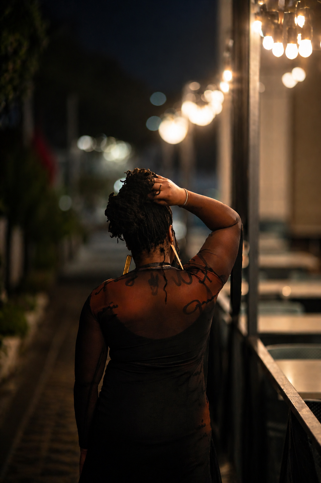 Woman standing on a street at night, looking into a store window.