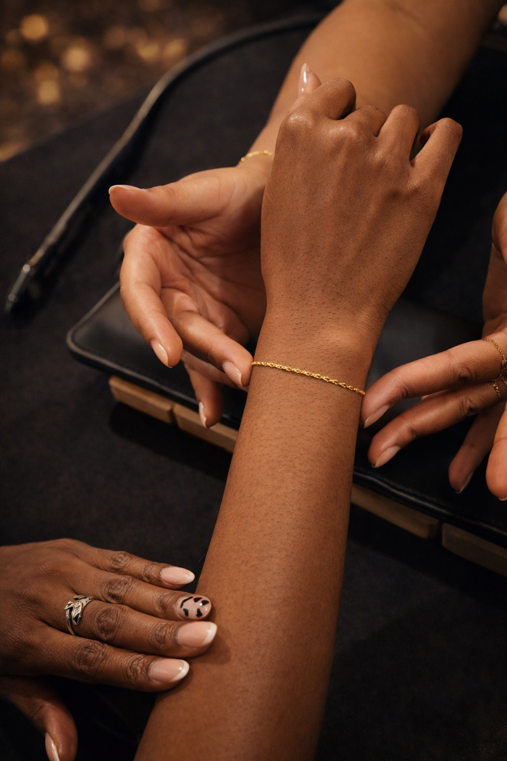 Close-up of multiple hands with jewelry on a dark surface