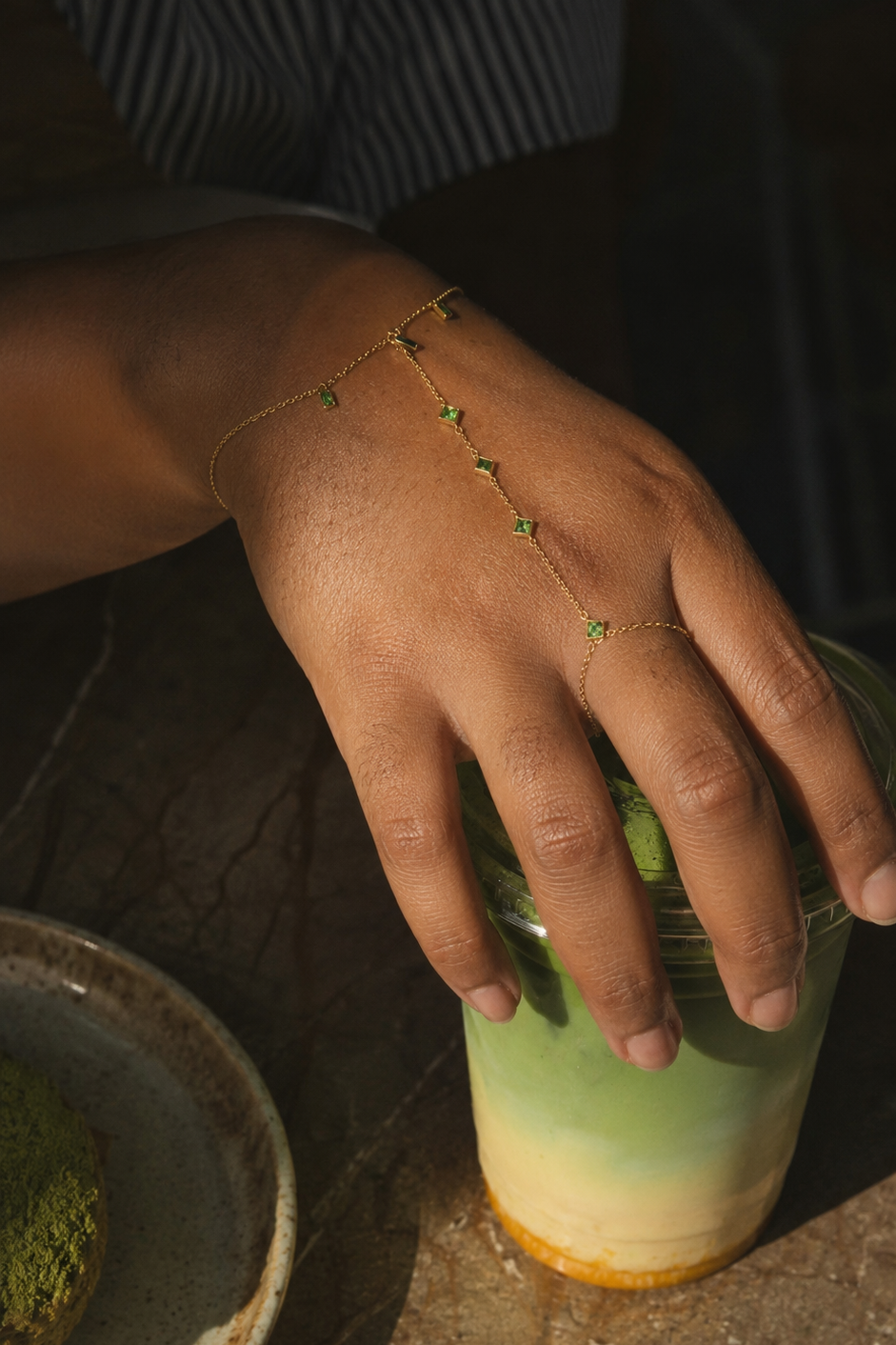 Hand Chain holding a green glass with a dark background