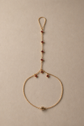 Gold custom handchain with red beads on a beige background