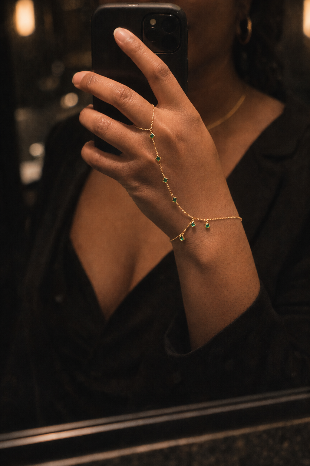 Woman wearing gold handchain with green cz crystal bezel set links