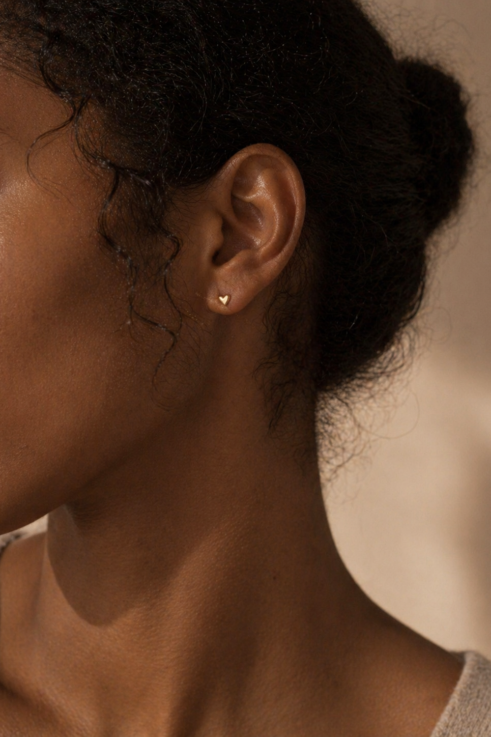 Woman wearing solid gold tiny heart studs