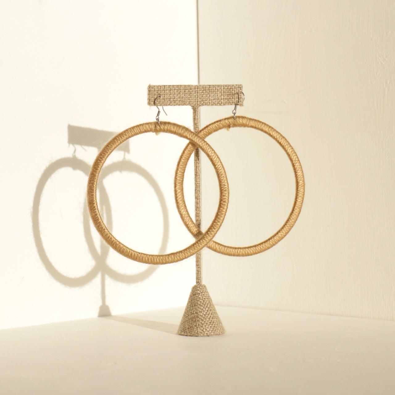 A pair of The Kommon statement hoop earrings from OlaNti Jewelry House, featuring a structured, oversized hoop design, displayed elegantly against a neutral background.