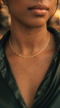 Close-up of a person wearing a gold necklace with a blurred background