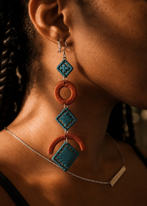 Close-up of a person wearing a unique earring with blue and orange geometric design.