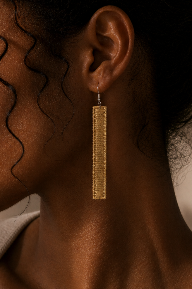 Close-up of a woman wearing gold earrings with a neutral background
