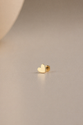 Gold heart-shaped flatback stud on a beige background