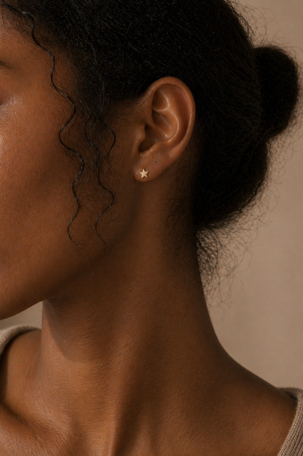 A woman wearing 14k gold star stud earrings