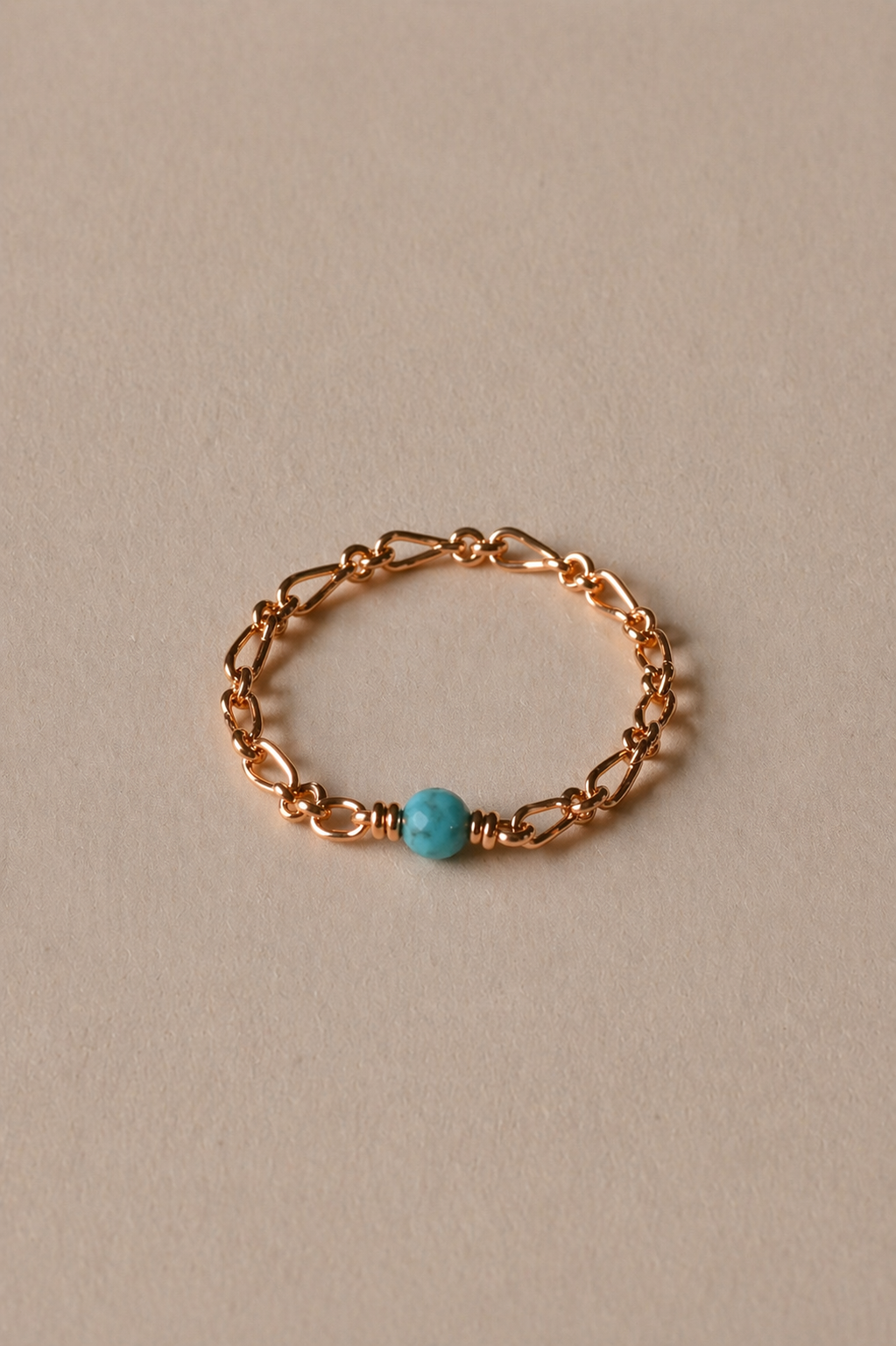 Gold chain ring with a turquoise on a beige background